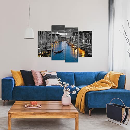 Modern living room with blue sofa, wooden table, and canal artwork on wall.