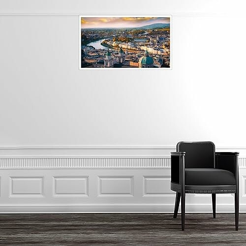 Framed cityscape artwork on a white wall above a black chair