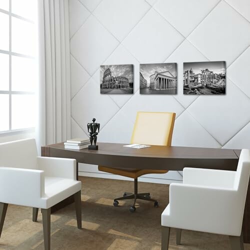 Modern office with three black and white artworks on the wall, a desk, and white chairs.