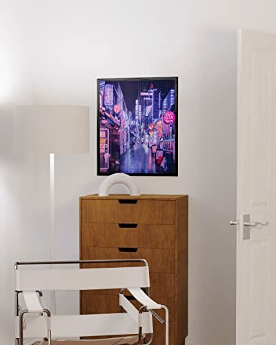 Modern interior with a cityscape poster, a lamp, a wooden dresser, and a white chair.