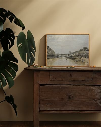 Wooden dresser with vintage painting and plant.