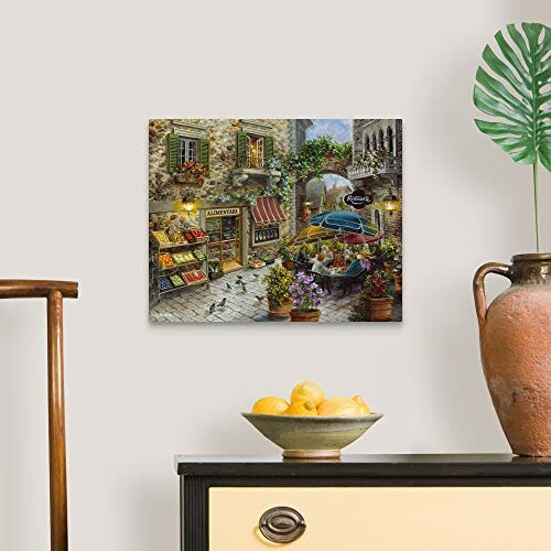 Wall art of a European street scene above a sideboard with a bowl of lemons.